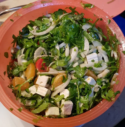 Frischer Salat mit Feta, Rucola und Zwiebeln in einer Schale